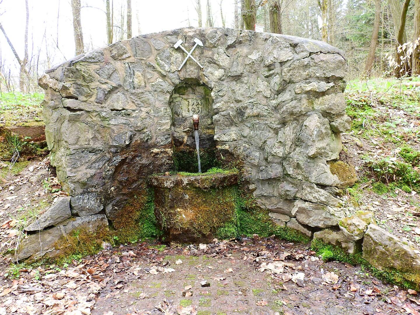 Oude stenen fontein in het bos met stromend water