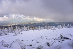 Verschneiter Brocken mit Wanderer. Winterlandschaft mit Blick ins Tal.